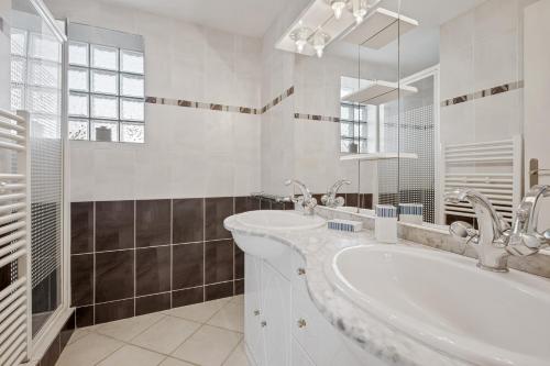 La salle de bains blanche est pourvue d'une baignoire et d'un lavabo. dans l'établissement Villa Vanille, à Châtelaillon-Plage
