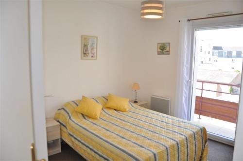 Un dormitorio con una cama con almohadas amarillas y una ventana en Bel appartement 2 chambres au centre-ville de PERROS-GUIREC - Ref 926, en Perros-Guirec