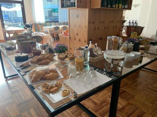 a glass table with a bunch of pastries on it at Hotel Posta in Aprica