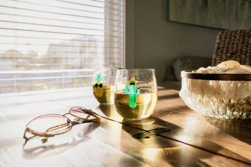 two glasses and a bowl on a wooden table at Green Family Bungalow! Beach Access, Pool, & Fishing Dock in Gulf Shores