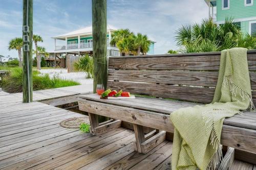 a wooden bench on a deck with a bowl of fruit at Green Family Bungalow! Beach Access, Pool, & Fishing Dock in Gulf Shores