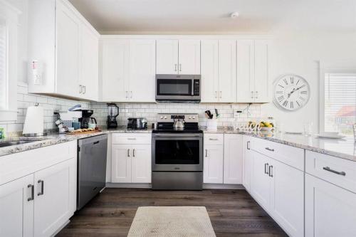 a white kitchen with a stove and a microwave at Green Family Bungalow! Beach Access, Pool, & Fishing Dock in Gulf Shores