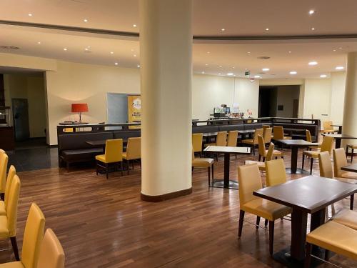 ein Restaurant mit Tischen und Stühlen und eine Bar in der Unterkunft SleepBEEONE AIRPORTHOTEL FRANKFURT MÖRFELDEN in Mörfelden-Walldorf