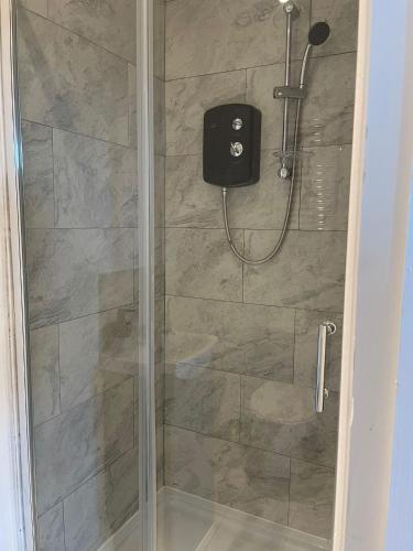 a shower with a glass door with a shower head at Cosy Studio in Manchester