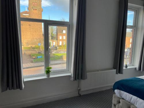 a bedroom with two windows with a view of a street at Cosy Studio in Manchester