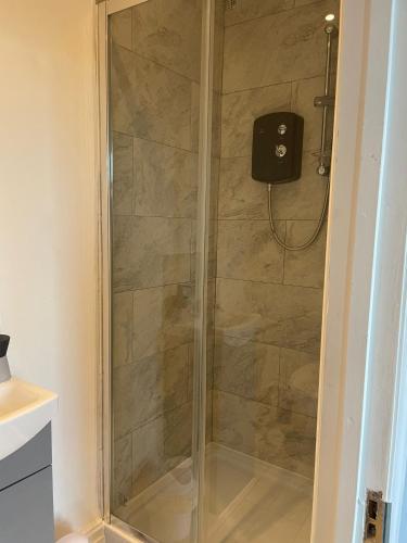 a shower with a glass door in a bathroom at Cosy Studio in Manchester