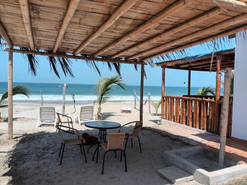 a patio with a table and chairs on the beach at Bungalows Sol y Mar in Canoas De Punta Sal