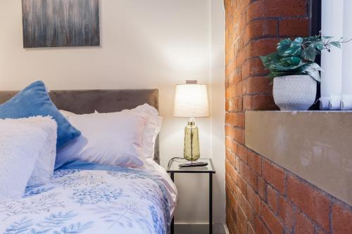 a bedroom with a bed and a brick wall at Outside Balcony Lux Apartment in Bradford