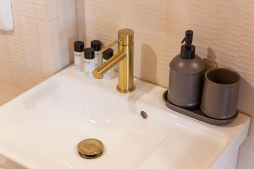 a sink with a gold faucet and a cup on it at Luxury Suite - Jacuzzi et Sauna in Arpajon