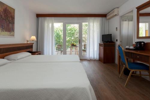 a bedroom with two beds and a desk and a window at Hotel Araxa - Adults Only in Palma de Mallorca
