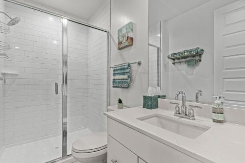 Baño blanco con aseo y lavamanos en AT YOUR SERVICE - Modern Amenities, Urban Location, Sophisticated Style, en Phoenix
