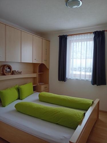 プフンツにあるFerienwohnung Familie Markのベッドルーム1室(緑の枕と窓付きのベッド2台付)