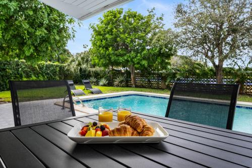 un vassoio di cibo su un tavolo accanto alla piscina di Coconut Road Beach Cottage Heated Pool a West Palm Beach