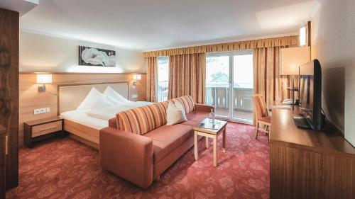 a hotel room with a bed and a couch and a television at Alpvita Piz Tasna in Ischgl