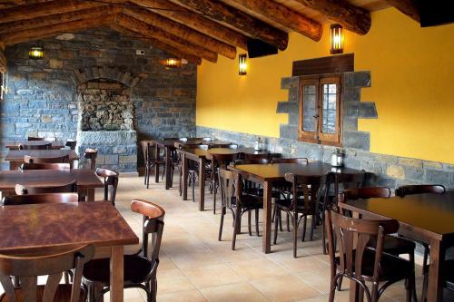a restaurant with wooden tables and chairs in a room at Mora de Nuei in Aínsa