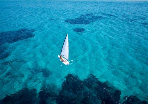 una piccola barca a vela nell'acqua blu di Calaserena Resort a Geremèas