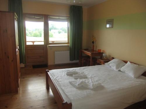 a bedroom with a large white bed and a window at Liedags Guesthouse in Jūrkalne