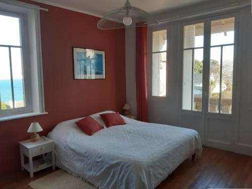 - une chambre avec un lit aux murs rouges et des fenêtres dans l'établissement Belle villa en granit rose VUE SUR MER à PERROS-GUIREC - Réf 943, à Perros-Guirec