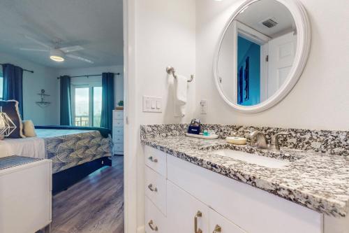 a bathroom with a sink and a mirror and a bed at Gulf Strand Resort 308 in St Pete Beach