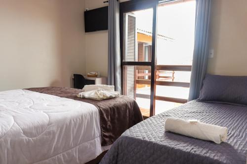 a bedroom with two beds and a window with a view at Pousada Paraíso in Cambará