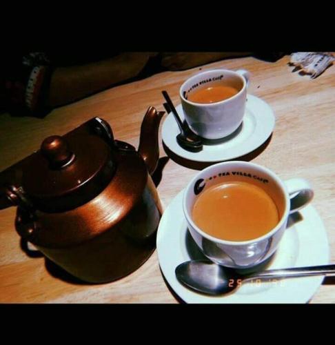two cups of tea and a teapot on a table at Motel Ambassador Multan in Multan
