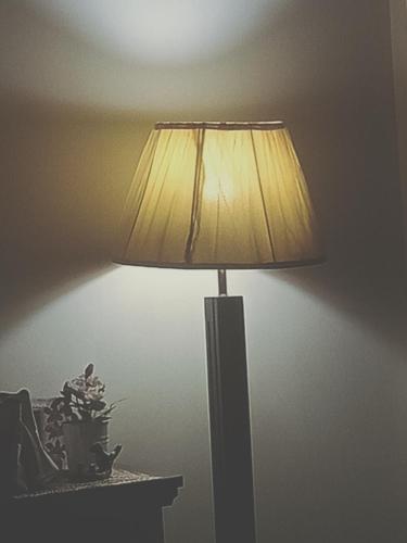 una lámpara sentada en una mesa junto a una pared en Motel Ambassador Multan, en Multán