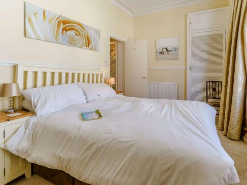 Un dormitorio con una cama blanca con un libro. en 5 Bed in Tenby FB151, en Tenby