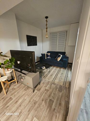 un salon avec un canapé bleu et une télévision dans l'établissement La Maison cosy de ville 3 chambres, à Marly