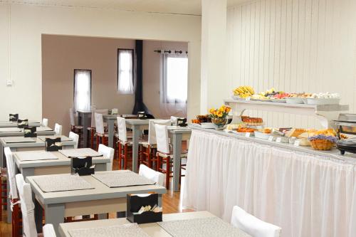 una sala da pranzo con tavoli bianchi e sedie bianche di Pousada Paraíso da Serra a Cambará