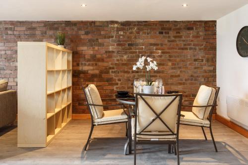 a dining room with a brick wall and a table and chairs at Broadgate Penthouse Apartment in Bradford