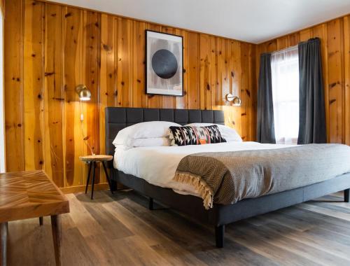 a bedroom with a bed and wood paneled walls at The Nightingale Motel in Pagosa Springs