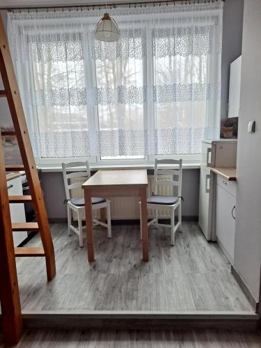 cocina con mesa, sillas y ventana en Niezależny apartament przy Parku Zdrojowym, en Kudowa-Zdrój