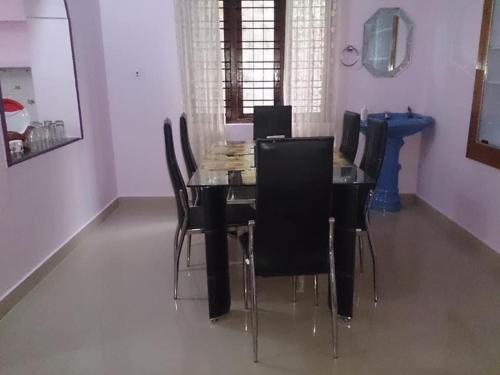 a dining room with a table and black chairs at Dhruva Homestay in Madikeri