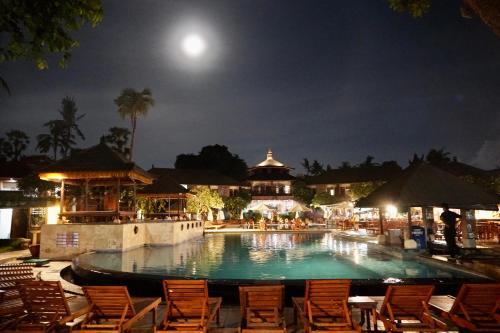a swimming pool at night with chairs and the moon at Galayanee’s Resort Apartment in Seminyak