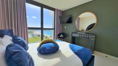 sypialnia z łóżkiem z niebieskimi poduszkami i lustrem w obiekcie Mullet Bay Suites - Your Luxury Stay Awaits w mieście Cupecoy