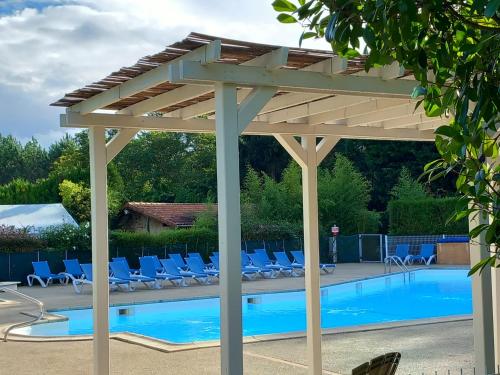 a wooden pergola over a swimming pool with chairs at Mobil-Home The Duck in Saint-Paul-lès-Dax