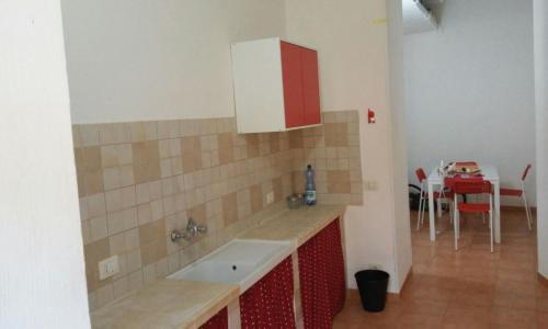 uma cozinha com um lavatório e um armário vermelho e branco em VIco Pittore em Modica