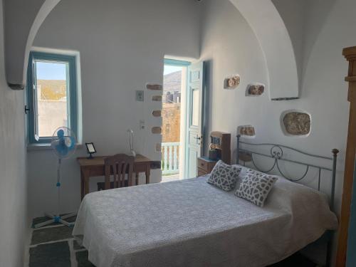 a white bedroom with a bed and a window at Folegandros-Cliffhouse in Chora Folegandros