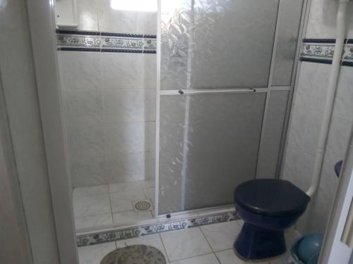 a bathroom with a shower with a blue toilet at Apartamento para casal. Perto do mar in Tramandaí