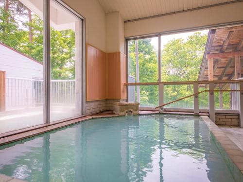 an indoor swimming pool with windows in a house at Hotel Oakhill in Zaō Onsen