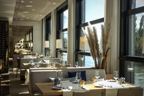 un restaurante con mesas, sillas y ventanas grandes en STAYY The River - contactless check-in, en Zúrich