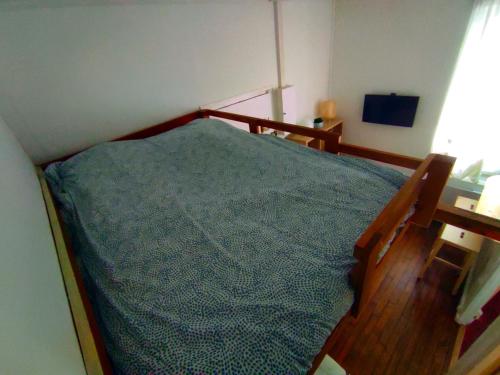 een slaapkamer met een houten bed en een blauwe deken bij Charmant Studio - 10 mn de Paris in Vitry-sur-Seine
