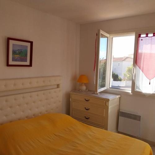 ein Schlafzimmer mit einem Bett, einem Fenster und einer Kommode in der Unterkunft Superbe Maison 3 chambres, wifi, climatisation, Narbonne Plage in Narbonne-Plage