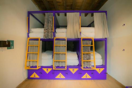 Viajero CDMX Centro Hostel في مدينة ميكسيكو: غرفة مع سرير بطابقين أرجواني مع المناشف