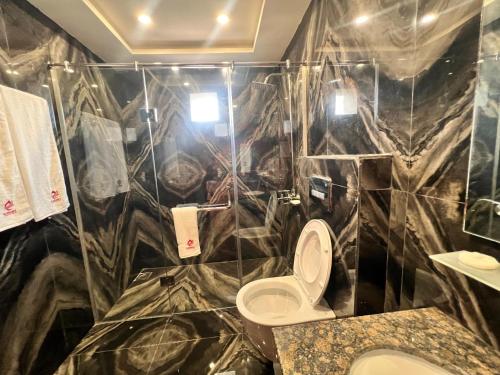 a bathroom with a toilet and a marble wall at Elegant Executive Suite in Multan
