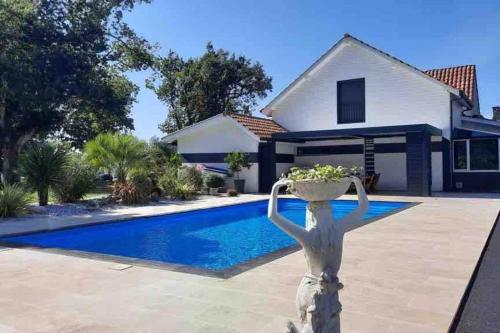 une maison avec une piscine et une statue d'une sirène dans l'établissement Villa piscine et jacuzzi, à Ychoux