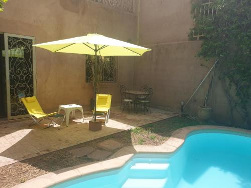 a patio with an umbrella and chairs and a pool at 3 bedrooms villa with private pool and enclosed garden at Marrakech in Marrakesh
