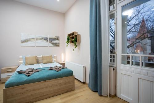 - une chambre avec un lit et une grande fenêtre dans l'établissement GoodWind Aparthotel - We believe in high standards, à Budapest