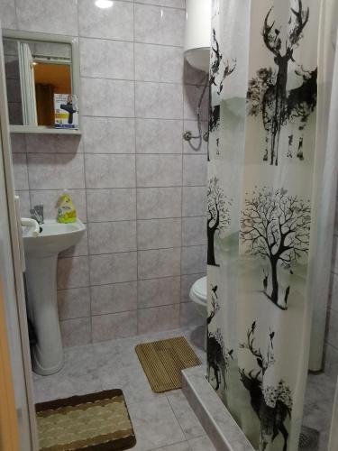 a bathroom with a shower curtain with trees on it at Rooms Jancic in Ulcinj