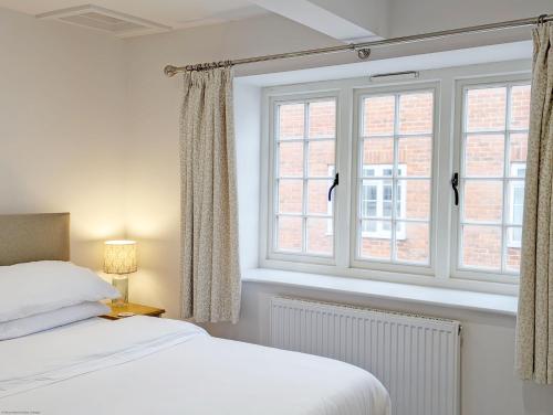 a bedroom with a bed and two windows at The Hive - Pet Friendly House - Emsworth in Emsworth